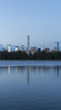 Manhattan Urban Skyline ve Reflection in Jacqueline Kennedy Onassis Reservoir in Central Park at Sunrise. New York 'ta. Amerika Birleşik Devletleri. Geceyle Gündüz Hızı. Dikey Video
