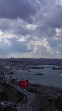 Baharda Bulutlu bir günde İstanbul 'un Beyoğlu ve Fatih ilçeleri. Golden Horn ve Galata Köprüsü. Hava görüntüsü. İnsansız hava aracı yukarı ve yana doğru uçuyor. Dikey Video