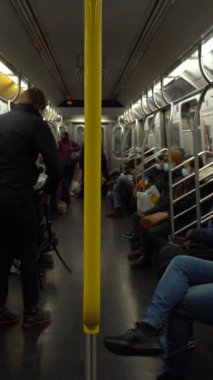 NEW YORK CITY, ABD - 21 HAZİRAN 2021: Coronavirus salgını sırasında metro treninde maske takanlar. Tren bir istasyona yaklaşıyor. Dikey Video