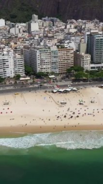 Güneşli bir günde Rio de Janeiro 'da. Copacabana Sahili ve Atlantik Okyanusu. Hava görüntüsü. Brezilya. İnsansız hava aracı yandan uçuyor. Yüksek açılı atış. Dikey Video