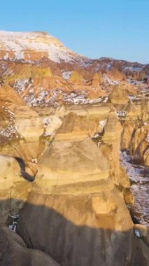 Kışın Kapadokya 'nın Kaya oluşumları Güneşli Gün' de. Karlı Tepeler ve Sütunlar. Hindi. Hava görüntüsü. Yörüngede. Dikey Video