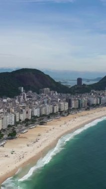 Güneşli bir günde Rio de Janeiro 'da. Copacabana Sahili ve Atlantik Okyanusu. Hava görüntüsü. Brezilya. Drone geriye doğru uçuyor. Dikey Video