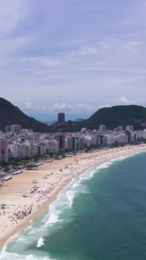 Güneşli bir günde Rio de Janeiro 'da. Copacabana Sahili ve Atlantik Okyanusu. Hava görüntüsü. Brezilya. Drone ileri ve yukarı doğru uçuyor. Dikey Video