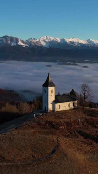 在阴云之上的太阳日 圣普里莫兹教堂和Felicijan教堂 朱利安 阿尔卑斯山 Jamnik Slovenia Europe 空中景观 垂直录像 — 图库视频影像