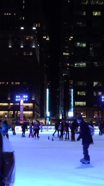 ニューヨークシティ アメリカ January 2021 冬の夕方にマンハッタンのブライアントパークでアイスリンクでマスクスケートを着ている人 垂直ビデオ — ストック動画