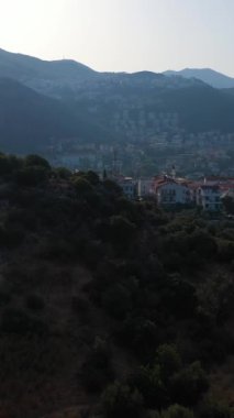 Güneşli bir günde Kas Kasabası, Deniz ve Dağların Beyaz Evleri. Antalya, Türkiye. Hava görüntüsü. Drone ileri ve yukarı doğru uçuyor. Şutu göster. Dikey Video