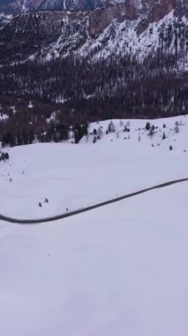 Giau Geçidi 'nde, kışın. Belluno, Dolomitler, İtalya. Hava görüntüsü. İnsansız hava aracı yandan uçuyor. Dikey Video