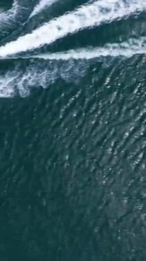 Denizde jet ski. Havadan Yukarıdan Aşağı Görünümü. İnsansız hava aracı yandan uçuyor. Dikey Video