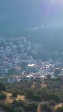 Güneşli bir günde Kas Town ve Dağları 'nın Beyaz Saray' ı. Antalya, Türkiye. Hava görüntüsü. İnsansız hava aracı yandan uçuyor. Dikey Video