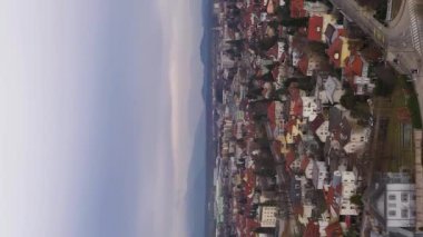 Ljubljana Şehri Bulutlu Gün 'de. Kırmızı kiremitli çatıları olan evler. Slovenya, Avrupa. Hava görüntüsü. Drone İleri Uçuyor. Dikey Video