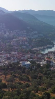 Güneşli bir günde Kas Kasabası, Deniz ve Dağların Beyaz Evleri. Antalya, Türkiye. Hava görüntüsü. İnsansız hava aracı yukarı ve geri uçuyor. Dikey Video