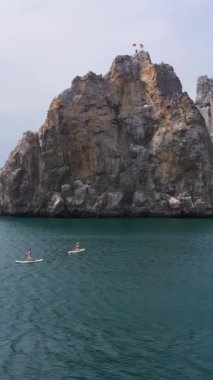 Sup yönetim kurulları, deniz ve uçurumlardaki insanlar. Hava görüntüsü. Drone yörüngede. Dikey Video
