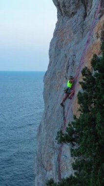 Kadın, Top Rope ile Tırmanış Kaya. Uçurum ve Deniz. Kırım, Rusya. Hava görüntüsü. Dikey Video