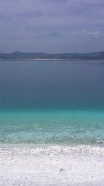 Güneşli bir günde Salda Gölü kıyısı. Krater Gölü. Burdur ilinin, Türkiye. Hava görüntüsü. Türk Maldivleri. İnsansız hava aracı alçaktan uçuyor. Kaypak Vuruşu. Dikey Video