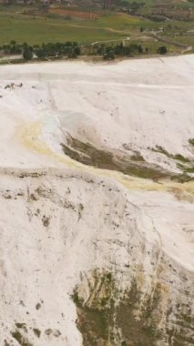 Pamukkale 'nin manzarası. Denizli, Türkiye. Hava görüntüsü. İHA geriye doğru uçar, yukarı doğru. Dikey Video