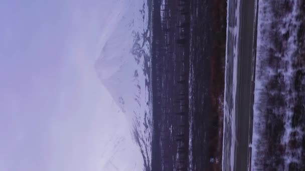 Auto Parks Highway Snow Capped Mountains Bewolkte Winterdag Tijdens Sneeuwval — Stockvideo