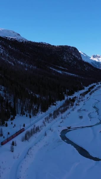 在瑞士阳光冬日的火车 Bernina铁路公司瑞士阿尔卑斯山 空中景观 飞行员向前飞 倾斜向上 真枪实弹垂直录像 — 图库视频影像