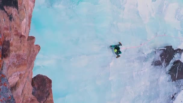 凍った滝の氷上昇 空中トップダウンビュー 男は氷のねじを置いている バルスコーン バレー キルギス ドローン フライズ サイドウェイ バーティカルビデオ — ストック動画