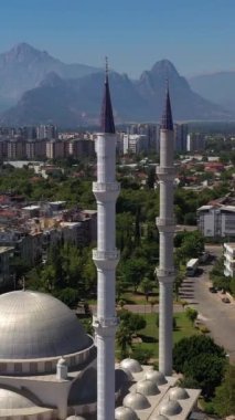Beyaz Cami, Şehir ve Dağlar. Antalya, Türkiye. Hava görüntüsü. İnsansız hava aracı yukarı ve geri uçuyor. Dikey Video