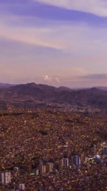 Akşam Alacakaranlığı 'nda La Paz Cityscape ve Illimani Dağı. Hava Hızı, Hiper Hata. Bolivya 'da. Mavi Saat. İnsansız hava aracı yandan uçuyor. Geniş açı. Dikey Video