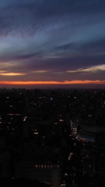 Gece vakti Buenos Aires City Skyline 'ı aydınlattı. Arjantin. Mavi Saat. İnsansız hava aracı yandan uçuyor. Dikey Video