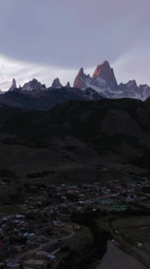 Turuncu Sırt çantalı Gezgin Fitz Roy Dağı 'na bakıyor. El Chalten Kasabası. Tepeler ve karla kaplı dağlar. And Dağları, Patagonya, Arjantin. Hava görüntüsü. Dikey Video