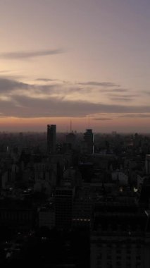 BUENOS AIRES, ARGENTINA - 20 ARALIK 2022: Akşam Alacakaranlığı 'nda Buenos Aires City Skyline. Arjantin. Mavi Saat. İnsansız hava aracı yandan uçuyor. Dikey Video