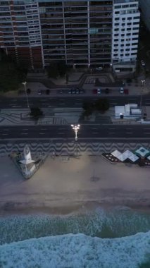 Rio de Janeiro City Sabah Alacakaranlığı 'nda. Copacabana Sahili, Avenida Atlantica ve Atlantik Okyanusu. Hava görüntüsü. Brezilya. İnsansız hava aracı yandan uçuyor. Dikey Video