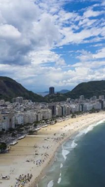 Güneşli bir günde Rio de Janeiro 'da. Copacabana Sahili ve Atlantik Okyanusu. Hava Hızı Hızı, Zaman Hızı. Brezilya. Drone ileri ve yukarı doğru uçuyor. Dikey Video