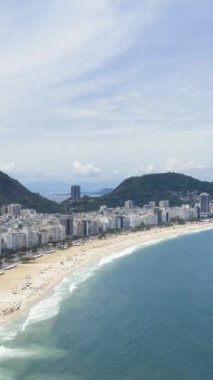 Güneşli bir günde Rio de Janeiro 'da. Copacabana Sahili ve Atlantik Okyanusu. Hava Hızı Hızı, Zaman Hızı. Brezilya. Drone ileri ve yukarı doğru uçuyor. Dikey Video