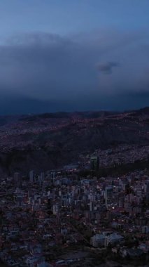 Akşam Alacakaranlığı 'nda parlayan La Paz Skyline. Hava görüntüsü. Zona Sur Bölgesi. Bolivya 'da. Mavi Saat. İnsansız hava aracı yandan uçuyor. Geniş açı. Dikey Video