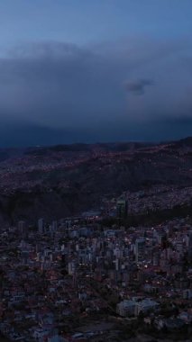 Akşam Alacakaranlığı 'nda parlayan La Paz Skyline. Hava görüntüsü. Zona Sur Bölgesi. Bolivya 'da. Mavi Saat. İnsansız hava aracı yandan uçuyor. Geniş açı. Dikey Video