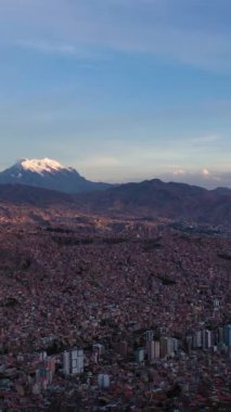 La Paz Cityscape ve Illimani Dağı. Hava görüntüsü. Bolivya 'da. Altın Saat. Drone ileri ve aşağı uçuyor. Geniş açı. Atış ayarlanıyor. Dikey Video