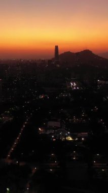 Sunset 'te parlayan Santiago City silueti. Hava görüntüsü. Akşam Alacakaranlığı. Mavi Saat. Las Condes Komünü. Şili. Drone İleri Uçuyor, Eğil. Şutu göster. Dikey Video