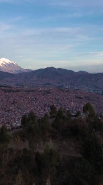 La Paz Cityscape ve Illimani Dağı. Hava görüntüsü. Bolivya 'da. Altın Saat. İHA ileri uçar, aşağı eğilir. Geniş açı. Atış ayarlanıyor. Dikey Video