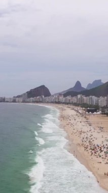 Rio de Janeiro Şehri. Copacabana Sahili ve Atlantik Okyanusu. Hava görüntüsü. Brezilya. Drone plajın üzerinde ileri uçuyor. Dikey Video