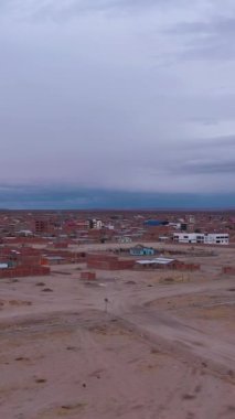 Uyuni Kasabası ve Bulutlu Gök. Hava görüntüsü. Bolivya 'da. Drone ileri ve yukarı doğru uçuyor. Geniş açı. Dikey Video