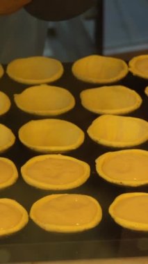Pastel De Nata tartlarında yumurta kreması dökülüyor. Portekiz Geleneksel Yumurta Kremalı Turta Pastası. Fırındaki tartlar. Dikey Video