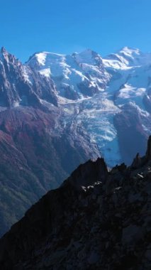 Güneşli bir günde Mont Blanc ve Aiguille du Midi Dağları. Fransız Alpleri, Fransa. Hava görüntüsü. İHA, Alçak Seviye 'deki Rocky Dağı' nın üzerinden ileri uçuyor. Dikey Video
