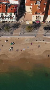 Susimbra Kasabası Deniz Önü. Binalar, sahil ve Atlantik Okyanusu. Portekiz. Hava Yüksek Açılı Atış. İnsansız hava aracı yandan uçuyor. Dikey Video