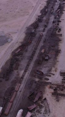 Uyuni Kasabası 'ndaki tren mezarlığı. Hava görüntüsü. Bolivya 'da. Drone İleri Uçuyor. Dikey Video