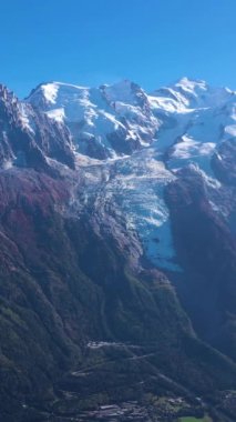 Güneşli bir günde Mont Blanc ve Aiguille du Midi Dağları. Fransız Alpleri, Fransa. Hava görüntüsü. İHA, Alçak Seviye 'deki Rocky Dağı' nın üzerinden geriye doğru uçuyor. Dikey Video
