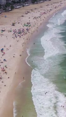 Güneşli bir günde Rio de Janeiro 'da. Copacabana Sahili ve Atlantik Okyanusu. Hava görüntüsü. Brezilya. Drone geriye doğru uçuyor. Dikey Video
