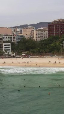 Rio de Janeiro Şehri. Atlantik Okyanusu 'ndaki Ipanema Plajı ve Sörfçüler. Hava görüntüsü. Brezilya. Yörüngede. Dikey Video
