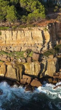 Güneşli bir günde ve Atlantik Okyanusu 'nda uçurumlar. Portekiz. Hava görüntüsü. İnsansız hava aracı yandan uçuyor. Dikey Video