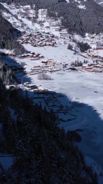 Uzungol Gölü kışın buzla kaplıdır. Ağaçlı Tepeler ve Dağlar. Hava görüntüsü. Trabzon ili, Türkiye. Drone İleri Uçuyor, Eğil. Şutu göster. Dikey Video