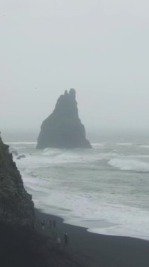 Reynisdrangar Kayaları ve Reynisfjall Dağı Bulutlu Gün 'de. Reynisfjara Sahili, İzlanda. Hava görüntüsü. Drone İleri Uçuyor. Dikey Video