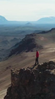 Adam İzlanda manzarasına bakarak Hver Bölgesi 'ndeki dağda duruyor. İzlanda. Hava görüntüsü. Drone yörüngede. Dikey Video