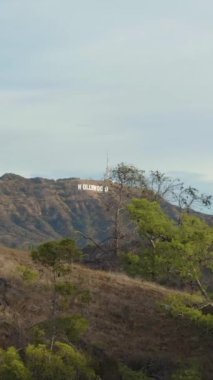 LOS ANGELES, ABD - 1 Aralık 2018 Hollywood Tabelası. Hollywood Hills, Kaliforniya, ABD. Hava görüntüsü. Drone ileri ve yukarı doğru uçuyor. Dikey Video