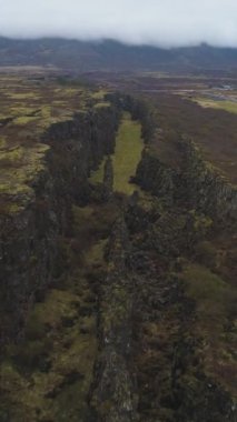 Yaz Bulutlu Günü 'nde Thingvellir Ulusal Parkı' nda çatlaklar ve çatlaklar. İzlanda. Hava görüntüsü. Şutu göster. Dikey Video
